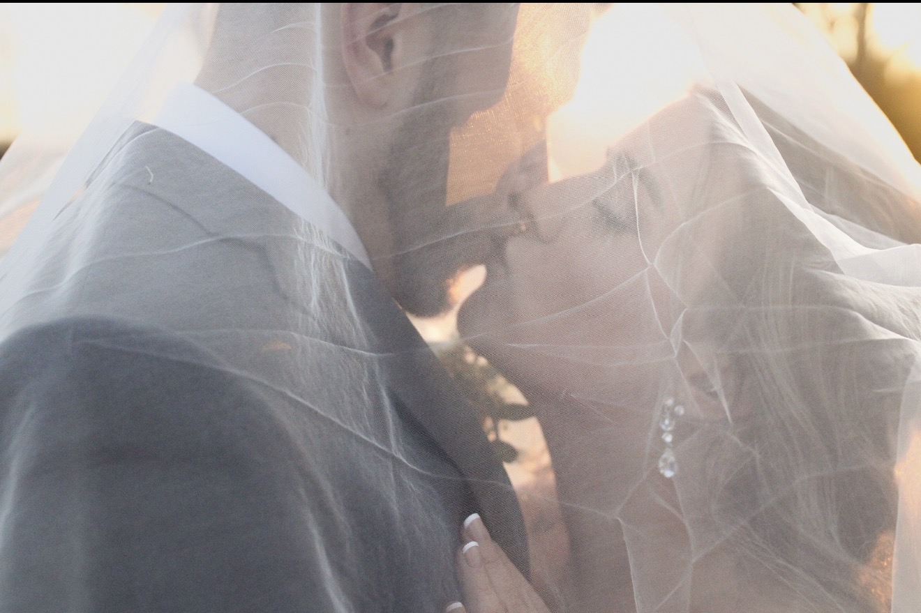Newlyweds kissing beneath the bride's veil